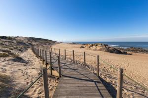 a wooden boardwalk on a beach next to the ocean at Aguda Beach Porto, Slow Travel Houses in Vila Nova de Gaia