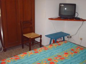 TarsiaにあるB&B Le Caselleのベッド、テレビ、椅子が備わる客室です。