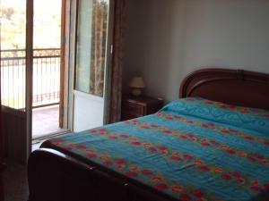 a bedroom with a bed with a blue comforter and a window at B&B Le Caselle in Tarsia