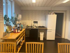 eine Küche mit einem Kühlschrank sowie einem Tisch und Stühlen in der Unterkunft Hattkalles Vandrarhem in Smedjebacken