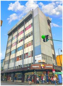 een groot gebouw op een straat met een verkeerslicht bij La Fortuna Roja in San José