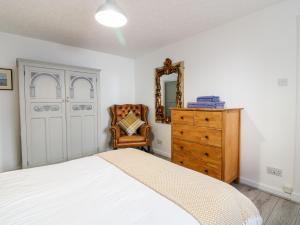 a bedroom with a bed and a dresser and a mirror at Seaspray Cottage in Buckie