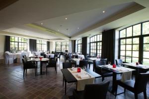 a dining room with tables and chairs and windows at Hotel De Lissewal in Ieper