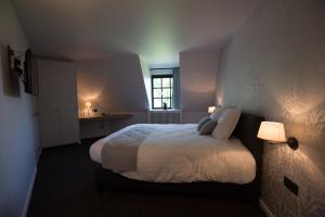 una camera da letto con un letto con lenzuola bianche e una finestra di Hotel De Lissewal a Ypres