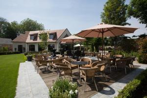 a patio with tables and chairs and umbrellas at Hotel De Lissewal in Ypres