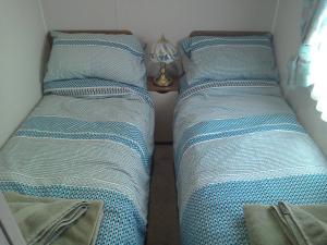twee bedden in een kleine kamer naast een tafel bij 54 Apple Grove in Exmouth