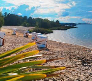 uma praia com mesas brancas e cadeiras na praia em schwimmende Ferienwohnung Rooftop em Elsterheide