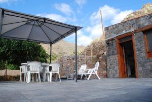 a group of white chairs and an umbrella on a patio at Casa Dos Barrancos C - Un Dormitorio, Parque Rural de Anaga in Santa Cruz de Tenerife
