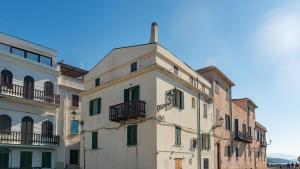an old white building with green shutters and balconies at Waterfront in Alghero