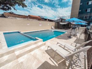 uma piscina com duas cadeiras e um guarda-sol em PRAIAPARK -APTO DIFERENCIADO-BETO CARRERO,MAR,WIFI300m,QUARTO DISNEY em Piçarras
