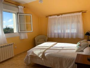 een slaapkamer met een bed, een raam en een stoel bij Apartamentos Turísticos San Breixo in Carballo