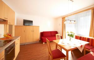 eine Küche und ein Wohnzimmer mit einem Tisch und einem roten Sofa in der Unterkunft Appartements Bergblick in Flachau