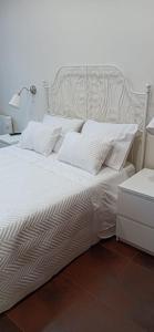 Elle comprend un grand lit blanc avec des draps et des oreillers blancs. dans l'établissement Casa da Ponte Velha, à Ponte de Lima