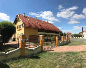 una casa amarilla con techo rojo y valla en Pitypang Apartman, en Gyula