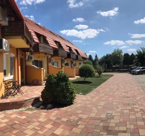 a building with a red roof and a brick driveway at Pitypang Apartman in Gyula