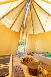 a large tent with a bench and a table in it at Les Tipis du Bonheur de Vivre in Brûlon