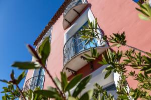 - un bâtiment rose et blanc avec un balcon dans l'établissement H14 Porto Frailis, à Àrbatax