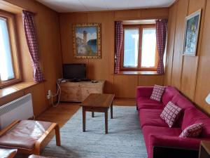 ein Wohnzimmer mit einem roten Sofa und einem Tisch in der Unterkunft Casa Vacanza Ponte Aino in Poschiavo