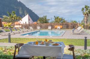 a table with food on it next to a pool at Quinta Vale Vitis in São Vicente