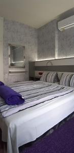 a bedroom with a large white bed with purple pillows at Lila Ház in Harkány