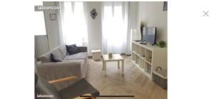 ein Wohnzimmer mit einem Sofa und einem Tisch in der Unterkunft F2 Rez de Chaussée Ô meublé de Pithiviers in Pithiviers