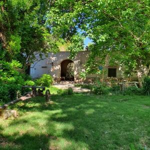 un edificio de piedra con un patio con césped y árboles en Rancho Por Fin en Barreal