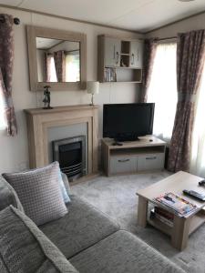 sala de estar con TV y chimenea en Luxury 2 bedroom caravan in stunning location en Pitlochry