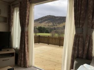 a sliding glass door with a view of a deck at Luxury 2 bedroom caravan in stunning location in Pitlochry