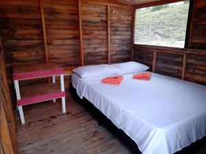 two beds in a log cabin with two windows at Mirador Valle de la Tatacoa in Villavieja