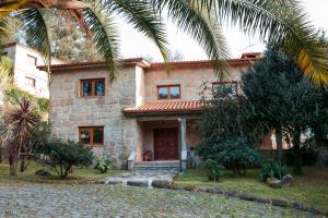 una casa de piedra con una palmera delante de ella en Casa das Flores, en Amares