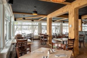 a dining room with tables and chairs and windows at Auberge l'Intermède du lac in Disraeli