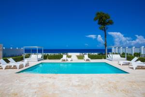 uma piscina com cadeiras e uma árvore e o oceano em Ocean Village Deluxe Resort & Spa em Sosúa