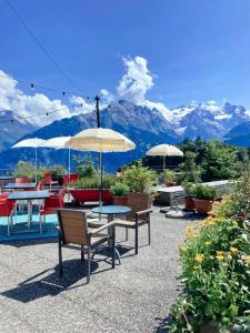 a patio with tables and umbrellas with mountains in the background at Hotel Gletscherblick in Hasliberg