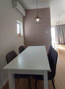 a white dining table with chairs in a room at Apartments Oliva in Podgora