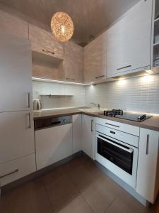 a white kitchen with white cabinets and a chandelier at Apartments Oliva in Podgora
