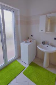 een badkamer met een wastafel, een toilet en groene tapijten bij Eden 96 in Camporosso