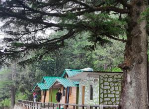 a man standing in front of a small house at Bluepine Cottages Pangot by Nature Nests in Nainital