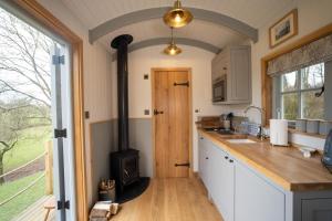 a kitchen with a wood stove in the middle at Somerset Shepherds Huts in Winsham