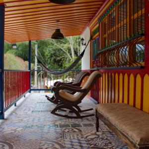 um quarto com duas cadeiras e um banco num alpendre em Casa de Campo las Serafinas em El Manzano