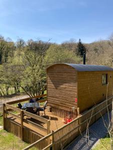 a wooden cabin with a table and a fence at Herdwick Shepherd Hut in Exeter