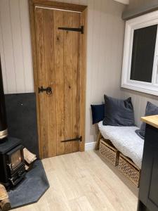 a room with a door and a bed and a stove at Herdwick Shepherd Hut in Exeter