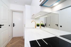 uma cozinha branca com um lavatório e um espelho em Tallinn Airport Studios by Revalhome em Talin