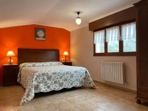 1 dormitorio con paredes de color naranja, 1 cama y ventanas en Santu Colás, en Corao