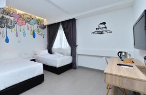 a room with two beds and a desk and a tv at Smile Hotel Shah Alam Seksyen 9 in Shah Alam