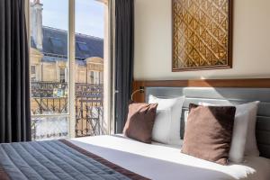 a bedroom with a bed and a large window at Hôtel Mayflower Opera in Paris