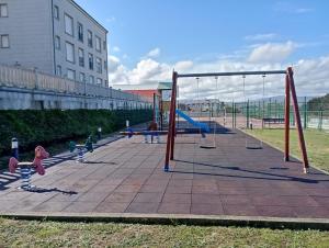 un parque infantil con columpios y equipo de juegos en Apartamento, Ático, Casa, PLAYA LAS CATEDRALES, en San Cosme de Barreiros