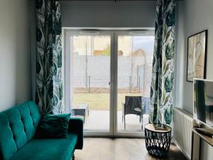 a living room with a blue couch and a sliding glass door at Apartament z ogródkiem i garażem in Poznań