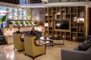 two women sitting in a living room with a tv at Grand King Hotel in Buenos Aires