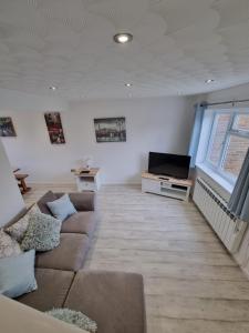 a living room with a couch and a tv at Anniversary Cottage- Country feel, close to Cromer in Northrepps