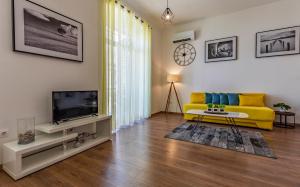 a living room with a yellow couch and a tv at Apartment Dream Pula - City Centre in Pula +3 photos